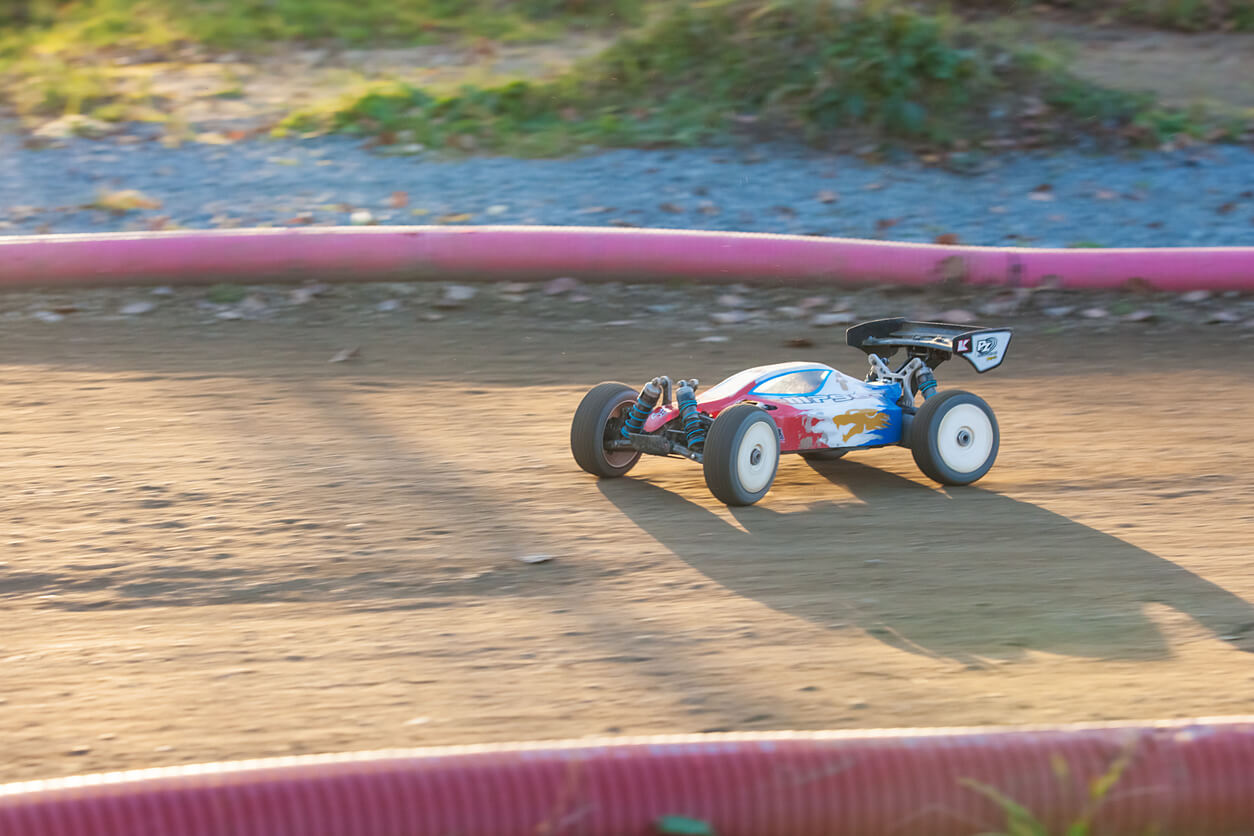 An image of an RC car driving on a sandy racetrack.