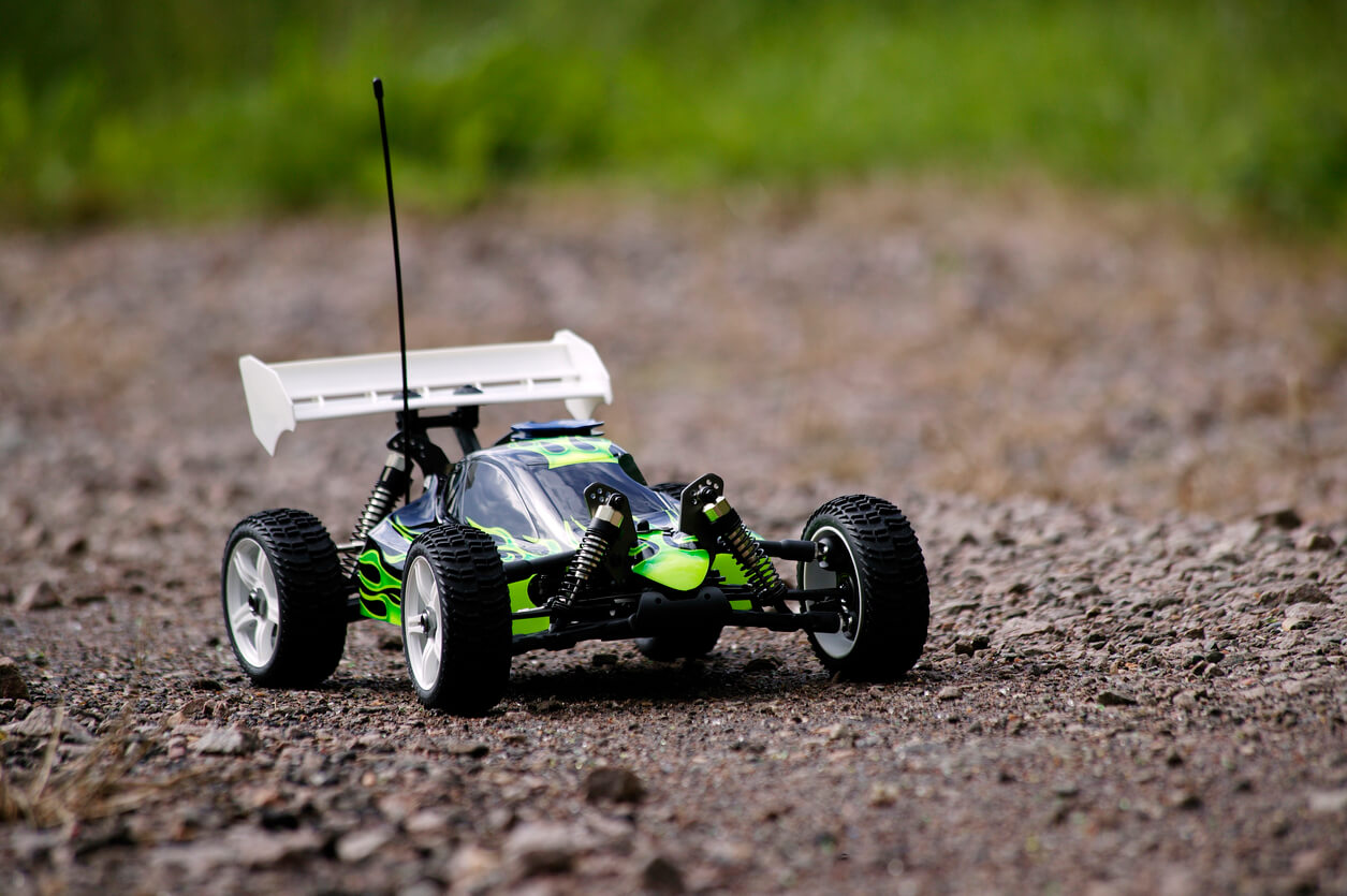 An outdoor image of a green RC buggy on a gravel road